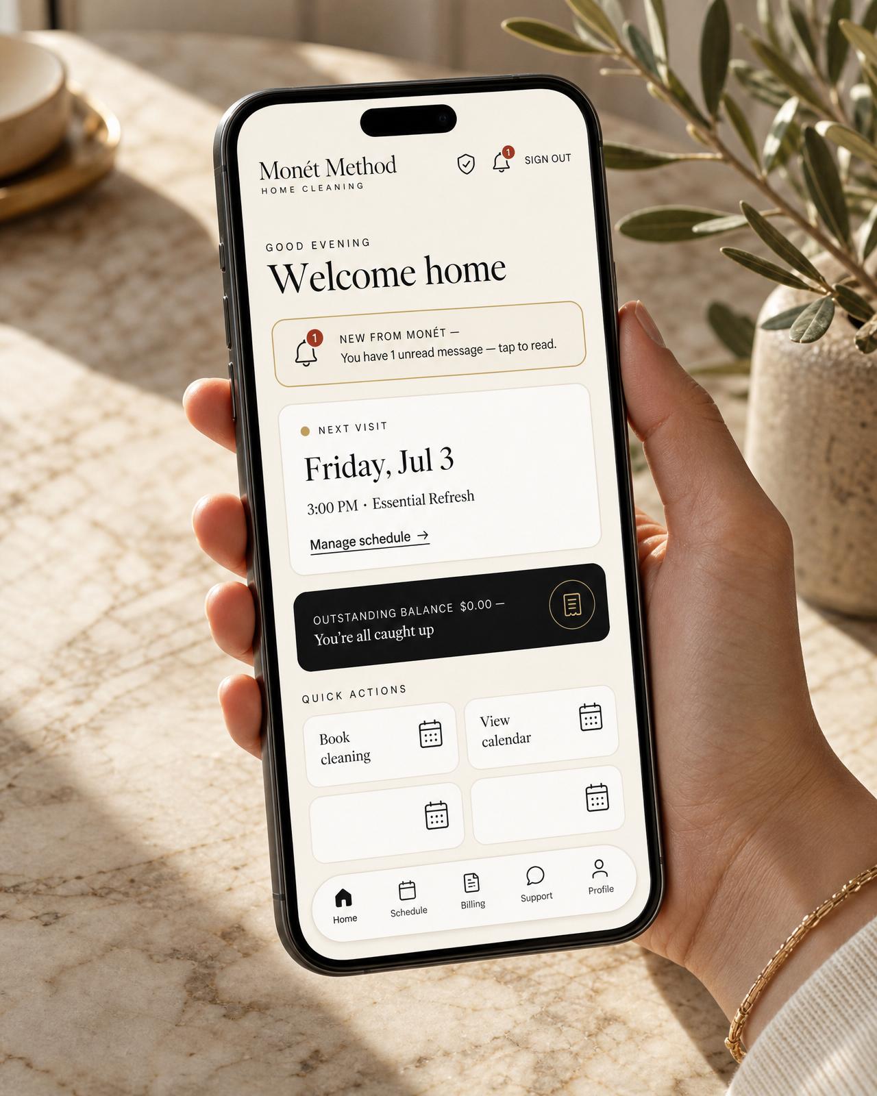 A hand holding a phone showing the Monet Method client app with upcoming home visits